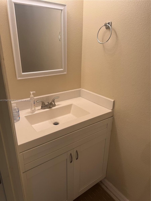 bathroom with vanity, wood finished floors, and a textured wall