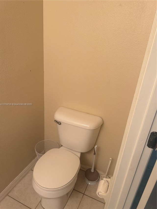 bathroom featuring tile patterned flooring, toilet, and baseboards