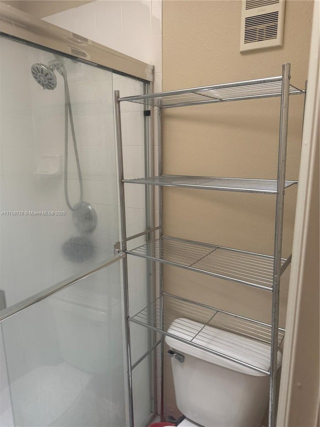 bathroom featuring visible vents, toilet, and a shower stall