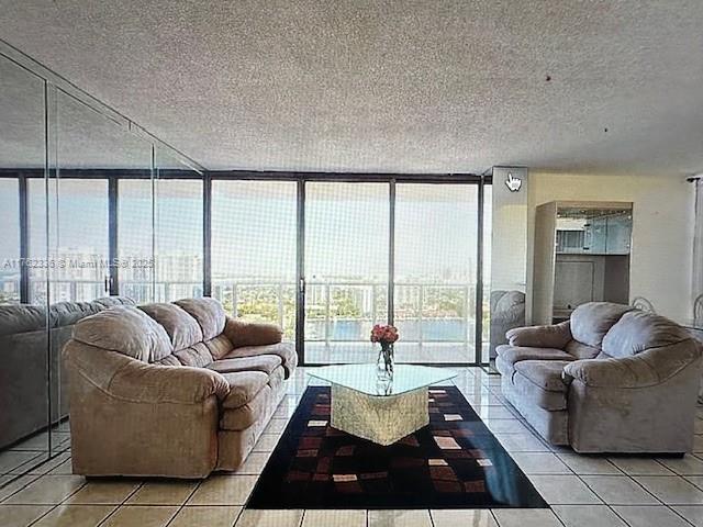 living area featuring light tile patterned floors, a textured ceiling, and expansive windows