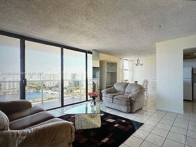 living area featuring light tile patterned floors, a textured ceiling, and a wall of windows