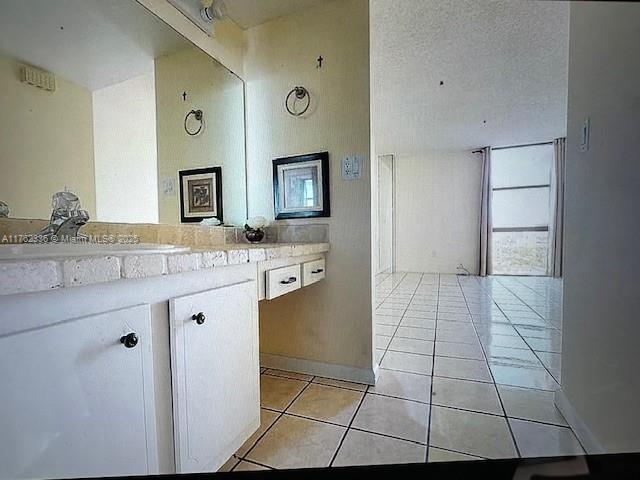 bathroom with tile patterned flooring, vanity, and a textured ceiling