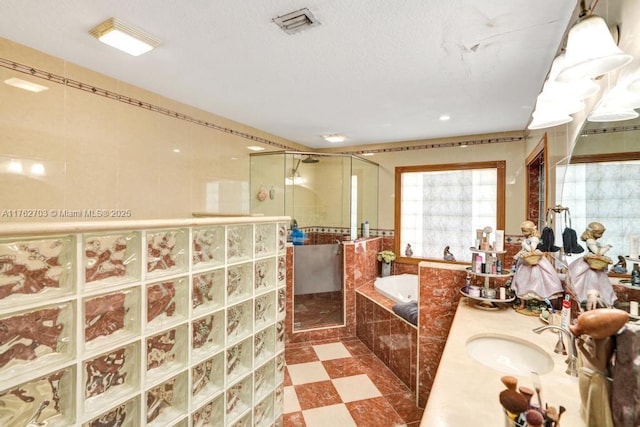 full bathroom featuring a stall shower, a textured ceiling, a bath, and tile patterned floors