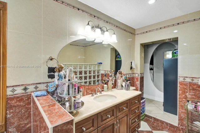 full bath with tile patterned flooring, a textured ceiling, tile walls, and vanity