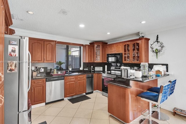 kitchen featuring a sink, dark countertops, stainless steel appliances, a peninsula, and glass insert cabinets