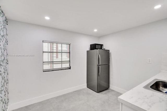 kitchen featuring black microwave, baseboards, light countertops, recessed lighting, and freestanding refrigerator