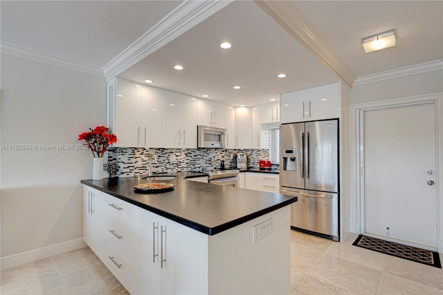 kitchen with ornamental molding, a sink, dark countertops, appliances with stainless steel finishes, and a peninsula