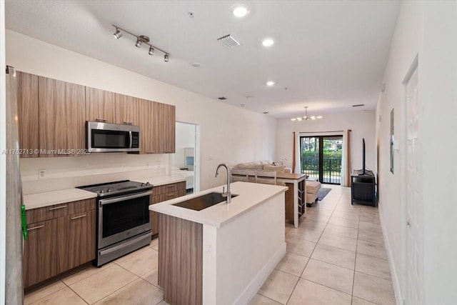 kitchen featuring open floor plan, a center island with sink, light tile patterned floors, stainless steel appliances, and a sink