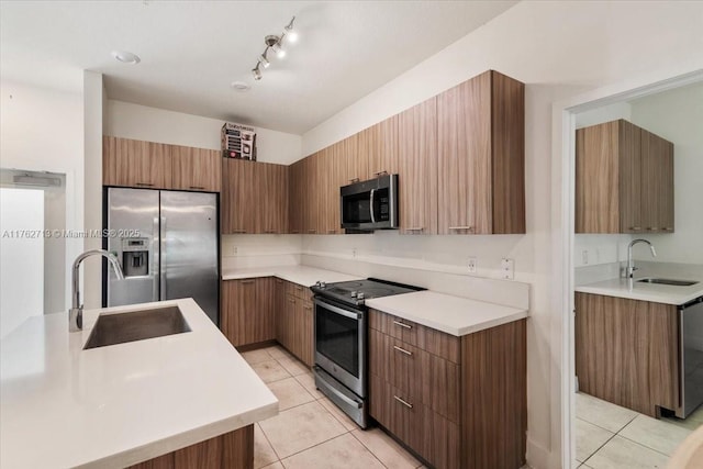 kitchen featuring light tile patterned flooring, appliances with stainless steel finishes, and a sink