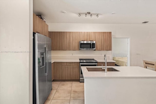 kitchen featuring light tile patterned floors, a sink, light countertops, appliances with stainless steel finishes, and modern cabinets