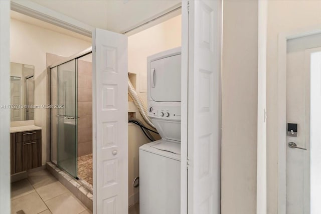 clothes washing area with light tile patterned floors, stacked washer and dryer, and laundry area