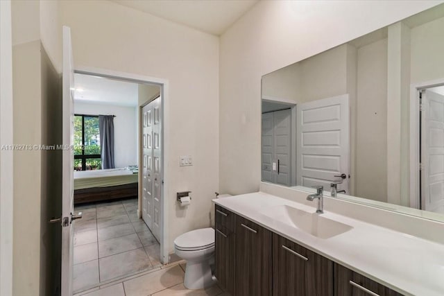 ensuite bathroom featuring tile patterned floors, connected bathroom, toilet, and vanity