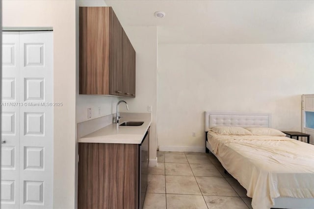 bedroom featuring light tile patterned flooring, baseboards, and a sink