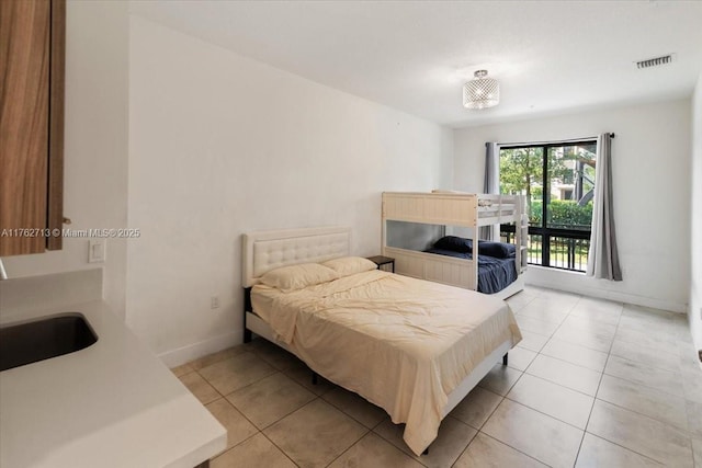 bedroom featuring light tile patterned floors, visible vents, baseboards, and a sink