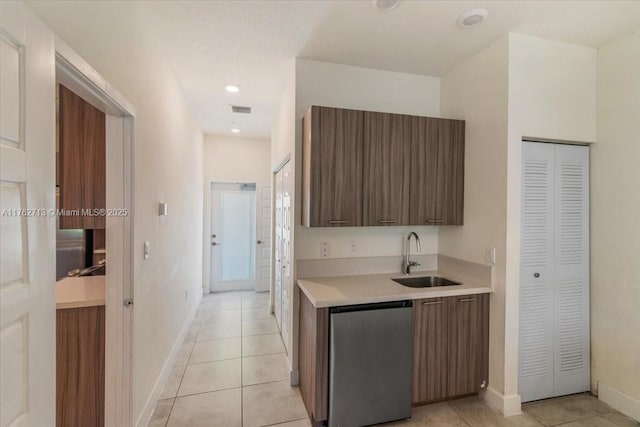 kitchen with light tile patterned floors, visible vents, refrigerator, a sink, and light countertops