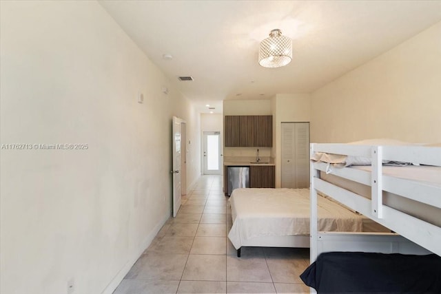 bedroom with visible vents, baseboards, light tile patterned flooring, a sink, and a closet