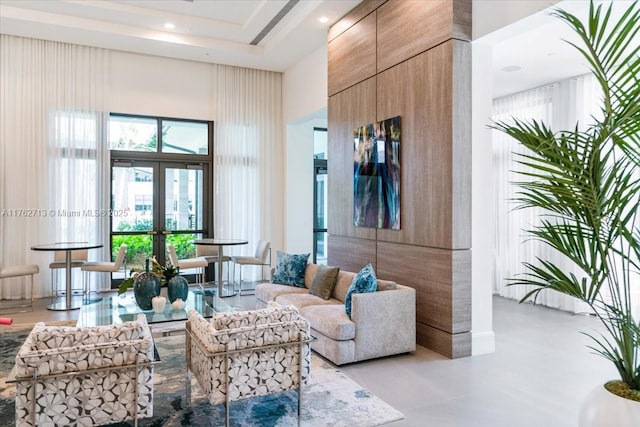 living room with a tray ceiling, french doors, and a towering ceiling