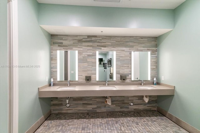 full bath with double vanity, baseboards, and a sink