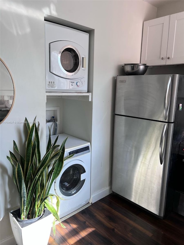 laundry room with baseboards, stacked washer and clothes dryer, dark wood-style flooring, and laundry area