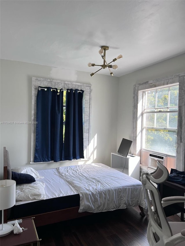 bedroom with cooling unit, wood finished floors, and a chandelier