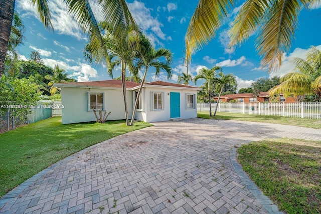 exterior space with decorative driveway, a yard, fence, and stucco siding