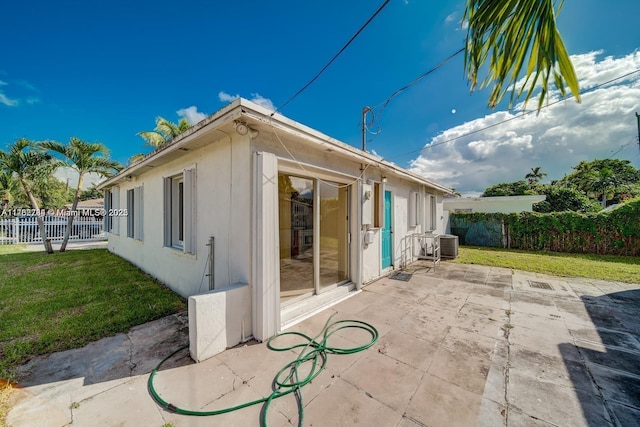 exterior space featuring central AC unit, a lawn, a patio, and fence