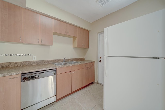 kitchen with a sink, freestanding refrigerator, light tile patterned flooring, light countertops, and dishwasher