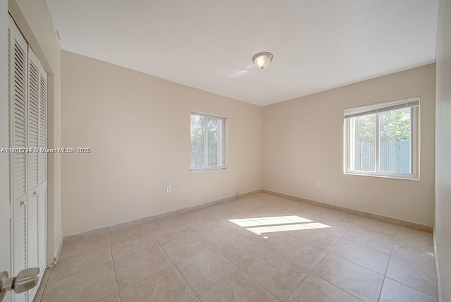 unfurnished room featuring light tile patterned flooring and baseboards