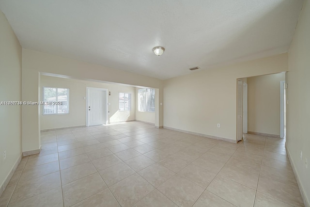 unfurnished room featuring light tile patterned floors, visible vents, and baseboards