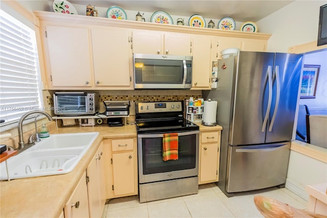 kitchen with a sink, stainless steel appliances, tasteful backsplash, and light countertops