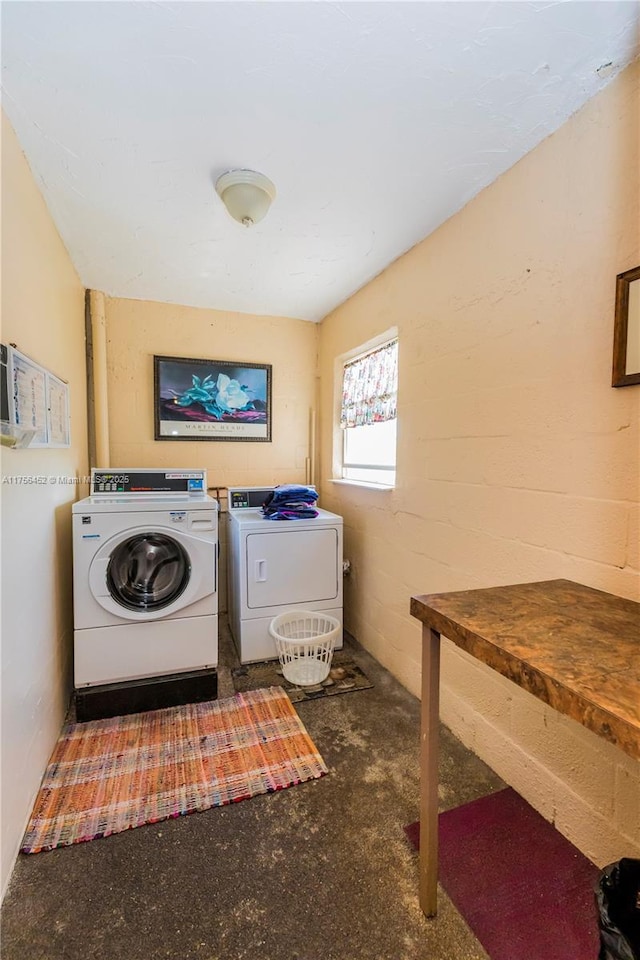 washroom with laundry area, concrete block wall, and washing machine and clothes dryer