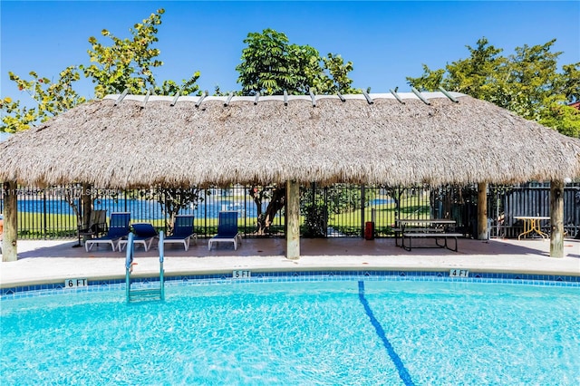 community pool with a gazebo, fence, and a patio area