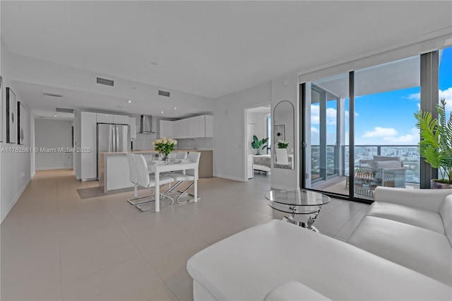 living room featuring light tile patterned floors, baseboards, visible vents, and expansive windows