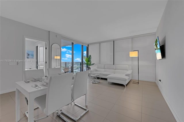 dining space featuring tile patterned flooring, a wall of windows, and baseboards