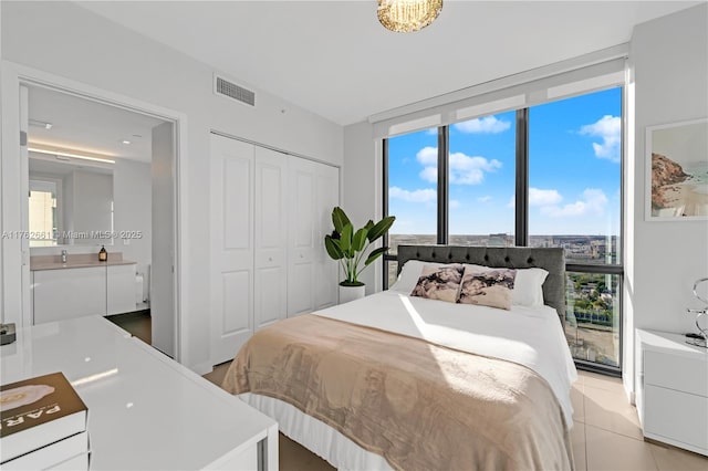 bedroom featuring multiple windows, light tile patterned flooring, visible vents, and a closet