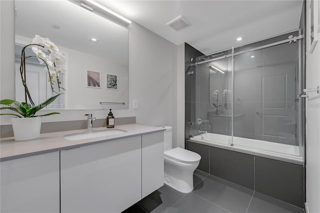 bathroom with tile patterned flooring, visible vents, bath / shower combo with glass door, toilet, and vanity