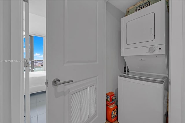 laundry area with tile patterned floors, stacked washer / dryer, and laundry area