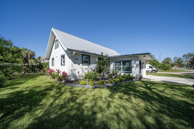 view of front of home featuring a front lawn, metal roof, and stucco siding