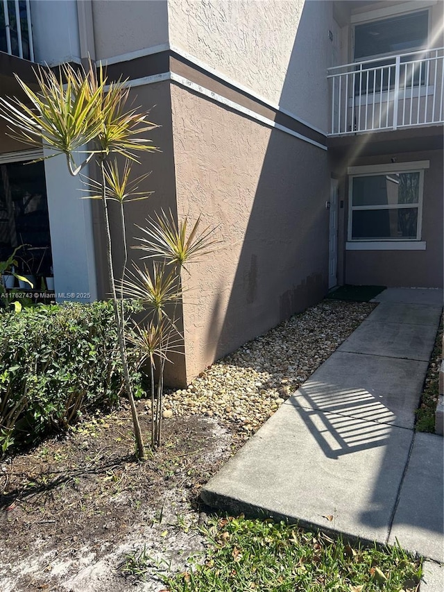 view of side of home with a balcony and stucco siding