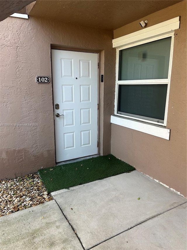 doorway to property featuring stucco siding