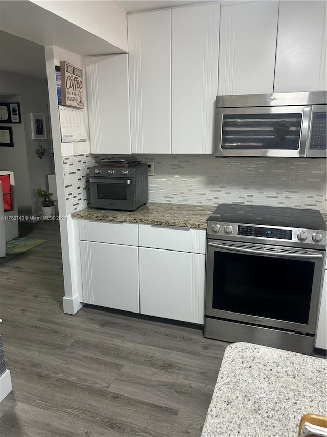 kitchen featuring decorative backsplash, white cabinets, stainless steel appliances, and dark wood-type flooring