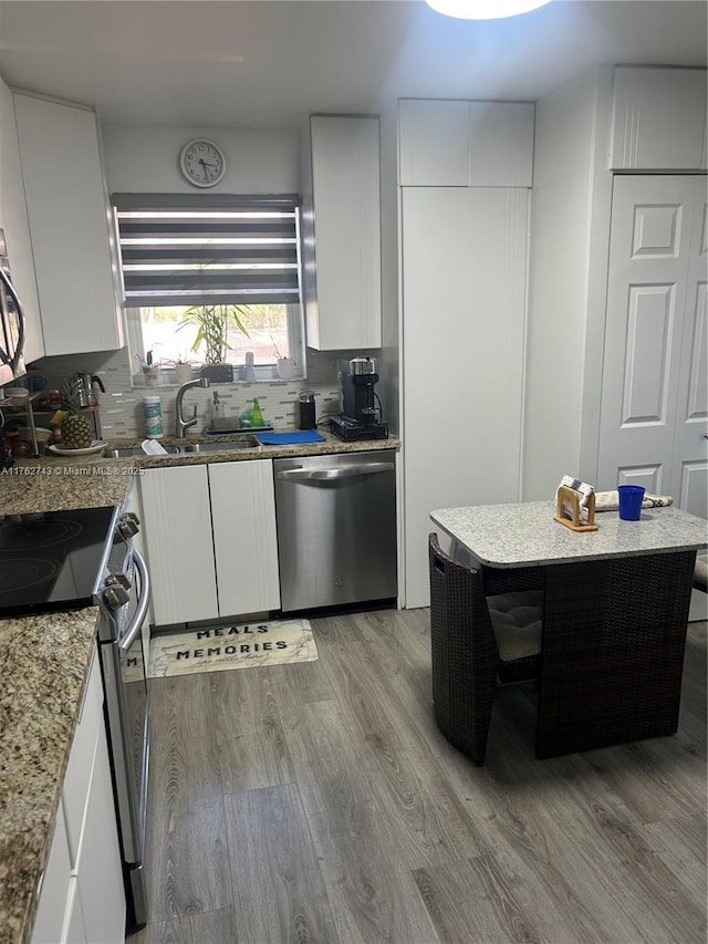 kitchen featuring a sink, appliances with stainless steel finishes, white cabinetry, tasteful backsplash, and light wood-type flooring