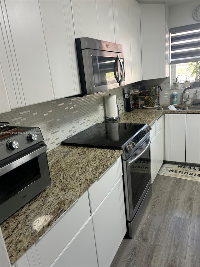 kitchen with backsplash, dark wood-type flooring, stone counters, stainless steel appliances, and white cabinetry