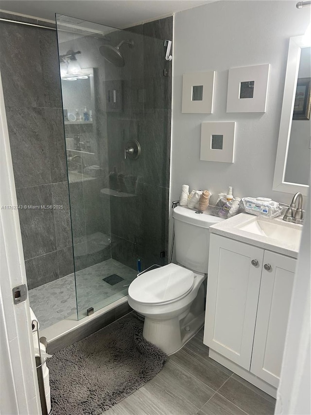 bathroom with vanity, toilet, and tiled shower