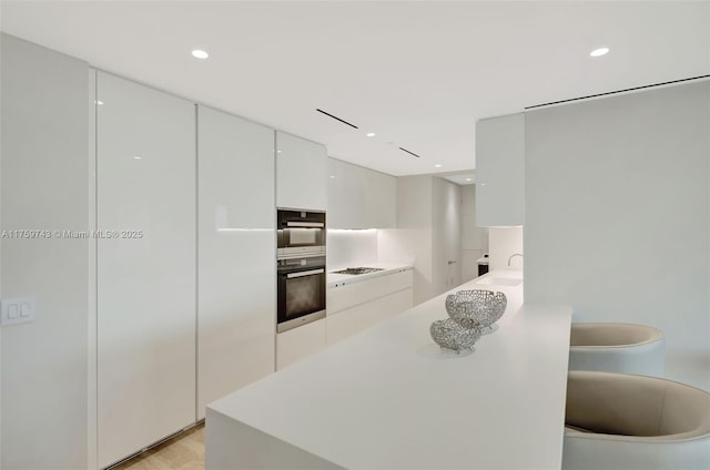 kitchen featuring recessed lighting, stainless steel appliances, light countertops, white cabinets, and modern cabinets