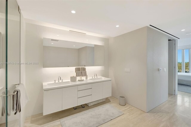 full bathroom with double vanity, recessed lighting, and a sink