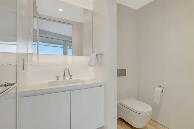 half bath featuring vanity, toilet, and wood finished floors