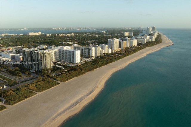 drone / aerial view featuring a water view, a city view, and a view of the beach