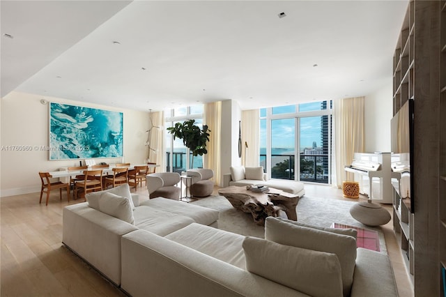 living room featuring expansive windows, baseboards, and light wood finished floors