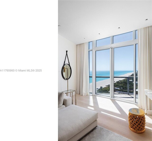 bedroom featuring wood finished floors, a water view, access to exterior, and floor to ceiling windows